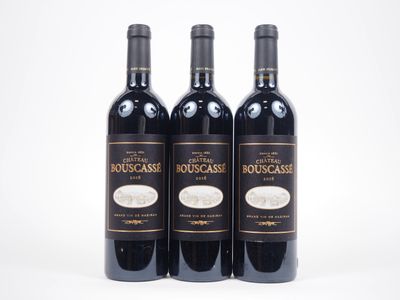trois bouteilles de vin rouge posées l'une à côté de l'autre sur une surface blanche