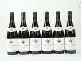 six bouteilles de vin sont alignées sur une surface blanche