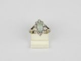 une bague en or blanc sertie d'une pierre verte entourée de diamants