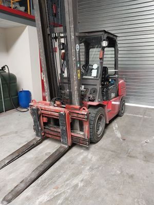 un chariot élévateur rouge dans un entrepôt avec un conteneur bleu