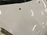 the hood of a white car with holes in the hood