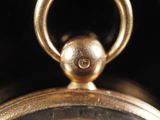 a close up of a gold pocket watch with a black background
