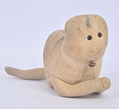 une petite peluche allongée sur une surface blanche
