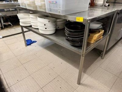 une grande table en métal sur laquelle sont posés de nombreux bols et casseroles