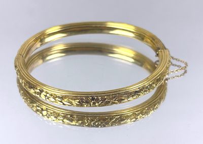 a close up of two gold bracelets on a white surface
