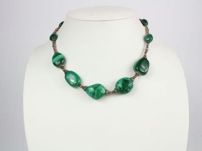 un collier avec des perles vertes sur un mannequin blanc