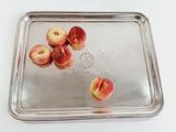 a metal tray with peaches on it on a white table