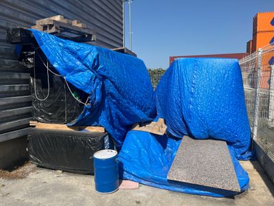 une bâche bleue posée par terre à côté d'une poubelle