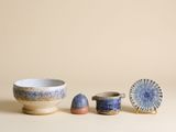 des bols et des tasses bleus et blancs posés sur une table, sur fond beige