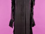 une robe noire posée sur un mannequin, sur fond rose