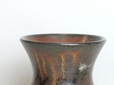 a brown vase sitting on a table with a white background