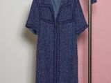 un manteau bleu suspendu à un porte-vêtements près d'un mur rose