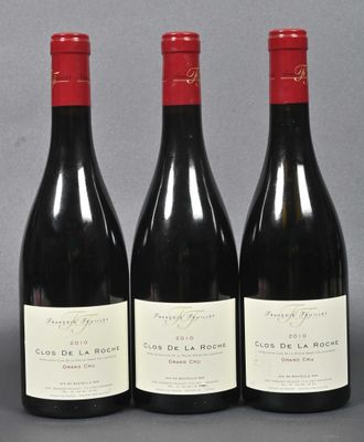 three bottles of red wine are lined up on a gray surface