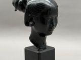 sculpture d'une tête de femme sur un socle en marbre noir