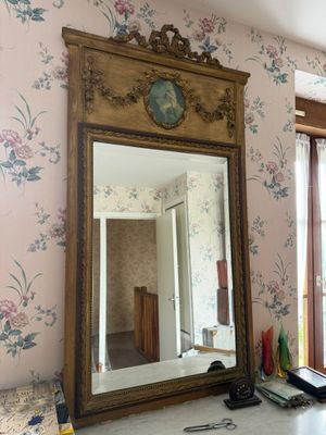 un miroir posé sur un bureau dans une pièce au papier peint à motifs floraux