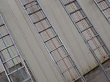 several ladders are lined up against a wall in front of a building