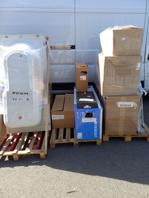 boxes and pallets are stacked on pallets in front of a white van