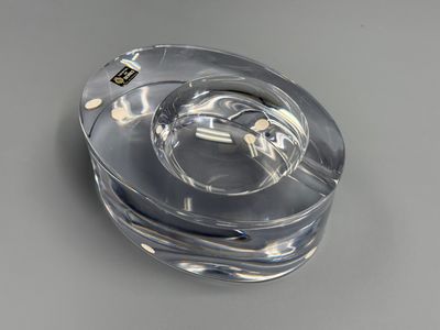 un cendrier en verre contenant une cigarette, posé sur une table