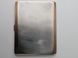 a silver cigarette case sitting on a white surface
