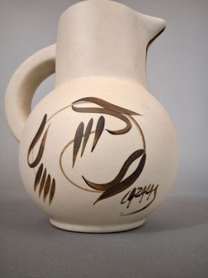 a white vase with a brown design on it