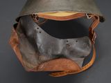 an old helmet with a leather strap and a metal helmet cover