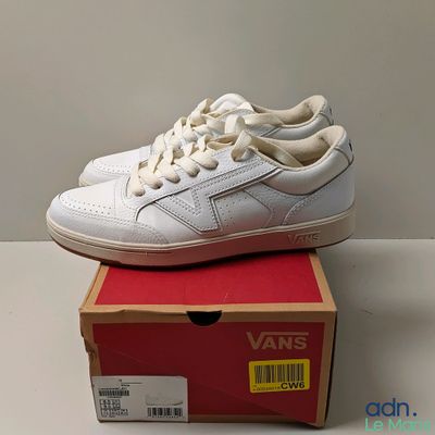 une boîte sur laquelle est posée une paire de chaussures blanches