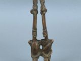 deux figurines en bronze représentant deux personnes se tenant par la main, l'une tenant l'autre dans ses bras