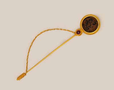 a close up of a gold stick with a brown stone on it
