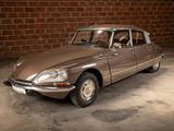 a brown car that is parked in front of a brick wall