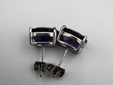 a pair of purple and silver earrings on a white surface