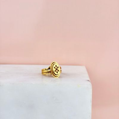 une bague en or posée sur un bloc de marbre, sur fond rose