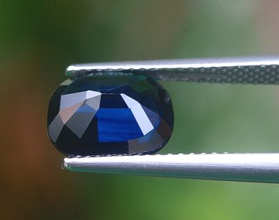un gros plan d'un diamant bleu tenu par une pince