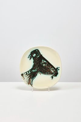 petite assiette ornée d'un oiseau, posée sur une surface blanche