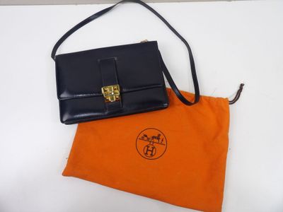 un sac à main noir et orange et une pochette orange sur un fond blanc