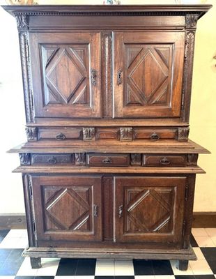 Une vieille armoire en bois trône sur un sol à carreaux noirs et blancs.