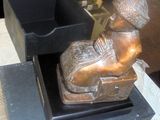 une statue en bronze représentant un garçon assis sur une chaise
