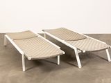 pair of loungers with woven seats in the middle of a concrete floor