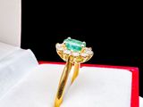 a gold ring with a green stone on top of a book