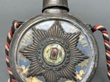 an old silver clock with a star on the front and a rope around it