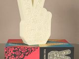quelqu'un fait le signe de la paix avec la main posée sur un livre