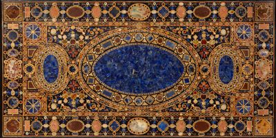 a close up of a blue and gold rug on a white surface