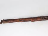 an old rifle with a wooden barrel on a white surface
