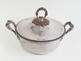 a silver pot with a handle on a white surface
