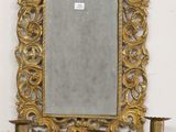 an image of a gold framed mirror on a wall next to a candelier