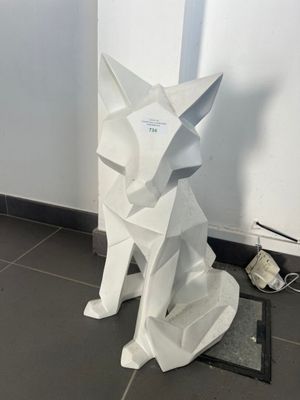 une sculpture blanche représentant un chien assis par terre