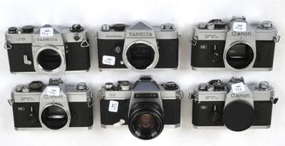 several old cameras are lined up in a row on a white surface