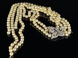 a white pearl necklace with a silver clasp on a black surface