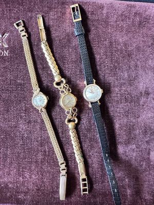three watches are sitting on a purple cloth on a table