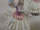 three figurines of a woman in a dress on a table