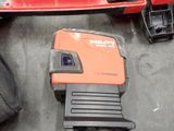 an orange and black machine and a black bag on the floor
